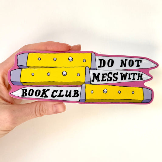 Hand holding a bumper sticker with 'Do Not Mess With Book Club' written on yellow switch blades, on a white background